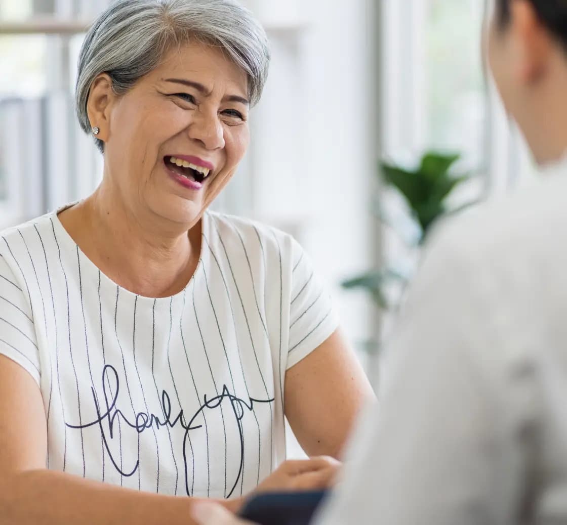 An elderly woman with grey hair talking to another person