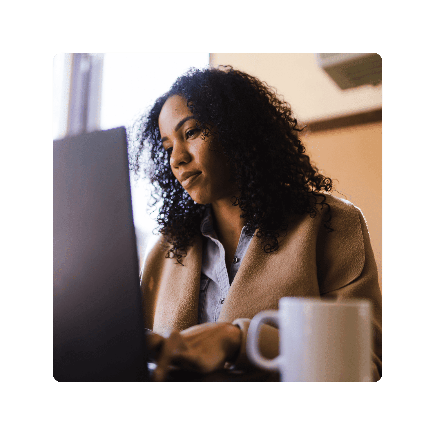 A lady in her brown jacket is looking at her laptop