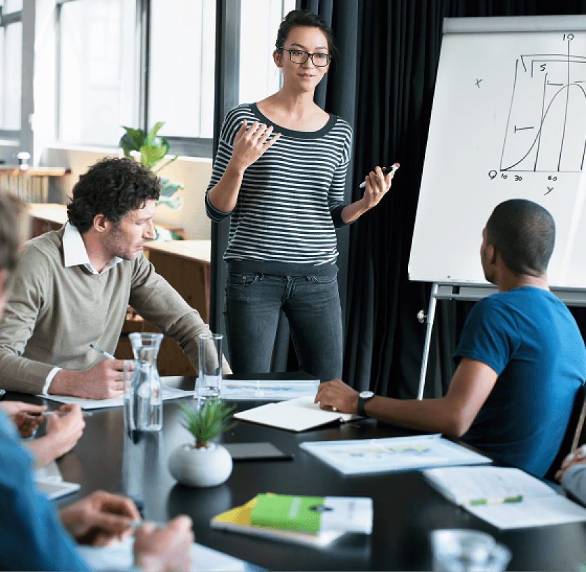A group of team members discussing in a meeting room in front of white board with a drawing on it